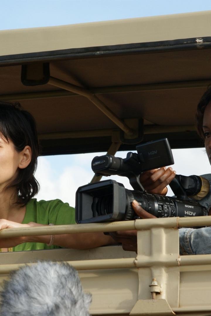 Zwei Frauen filmen aus einem offenen Geländewagen heraus.