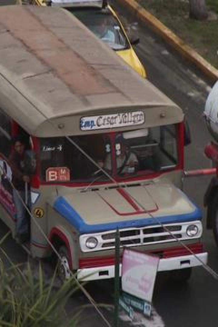 Ein beiger Bus der „Emp. Cesar Vallejo“ fährt auf einer Straße in Trujillo.