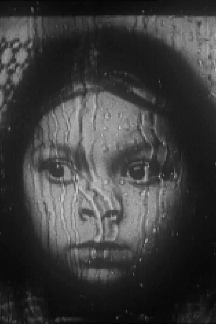 Das Gesicht eines Mädchens ist durch eine regennasse Fensterscheibe zu sehen.