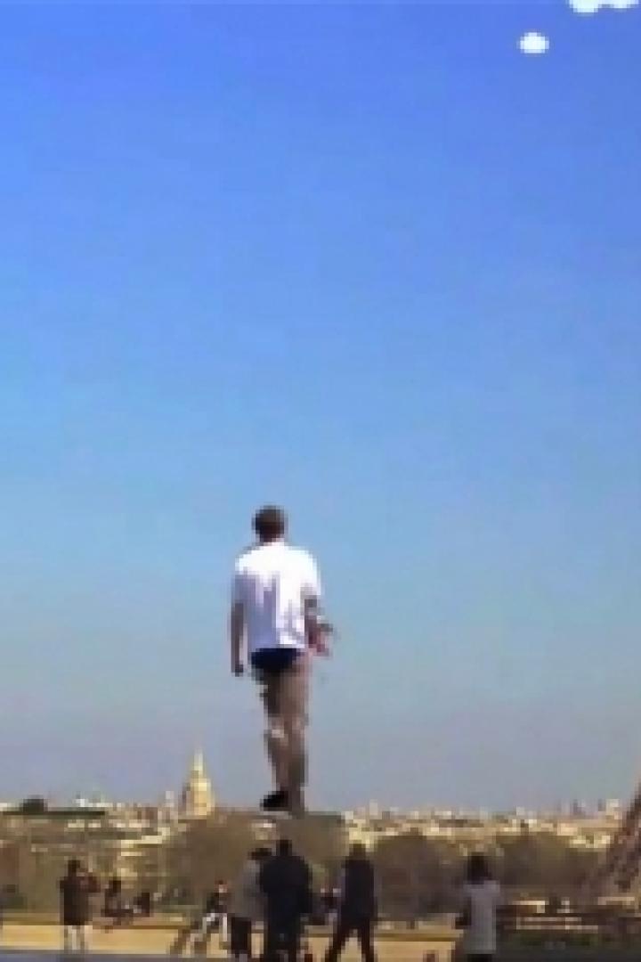 Ein Mann steht auf einem Sockel vor dem Eiffelturm in Paris.