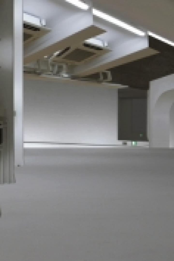 Ein leerer, weißer Raum mit Rohren und Lüftungsschächten an der Decke.