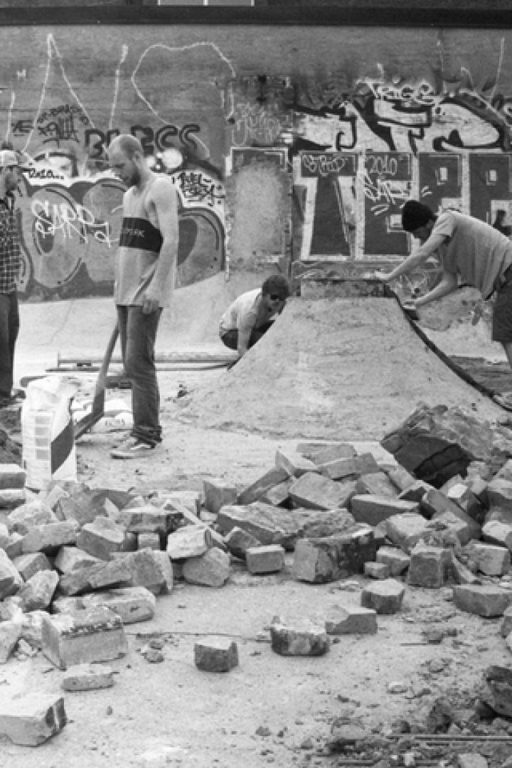 Eine Gruppe von Personen baut einen Skatepark mit Ziegelsteinen und Erde.