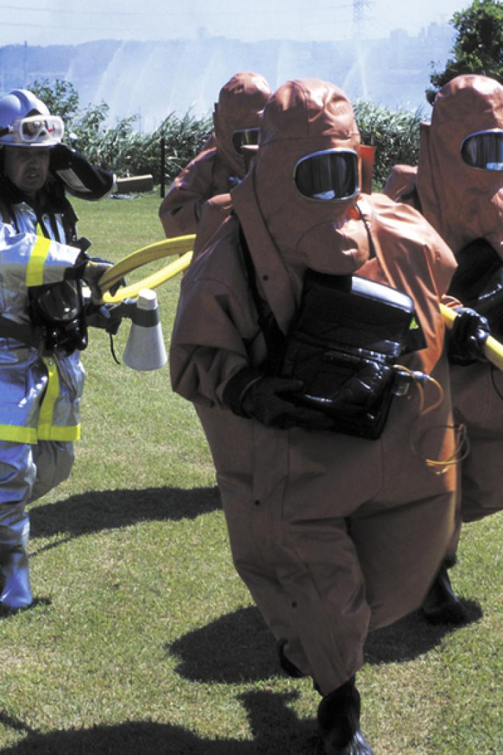 Eine Gruppe von Feuerwehrleuten in Schutzanzügen hält einen gelben Schlauch.