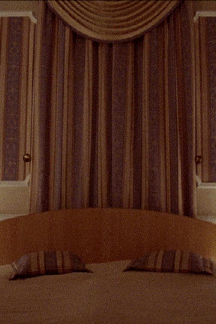 Ein Schlafzimmer mit einem Doppelbett und gestreiften Tapeten.