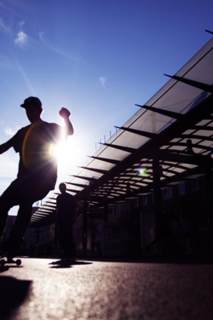 Ein Skateboardfahrer fährt auf einer sonnigen Straße entlang.