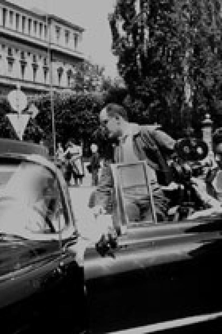 Ein Filmteam dreht eine Szene mit einem Auto auf einer Straße.