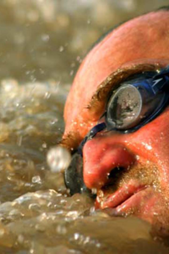 Ein Mann mit Schwimmbrille schwimmt im trüben Wasser.