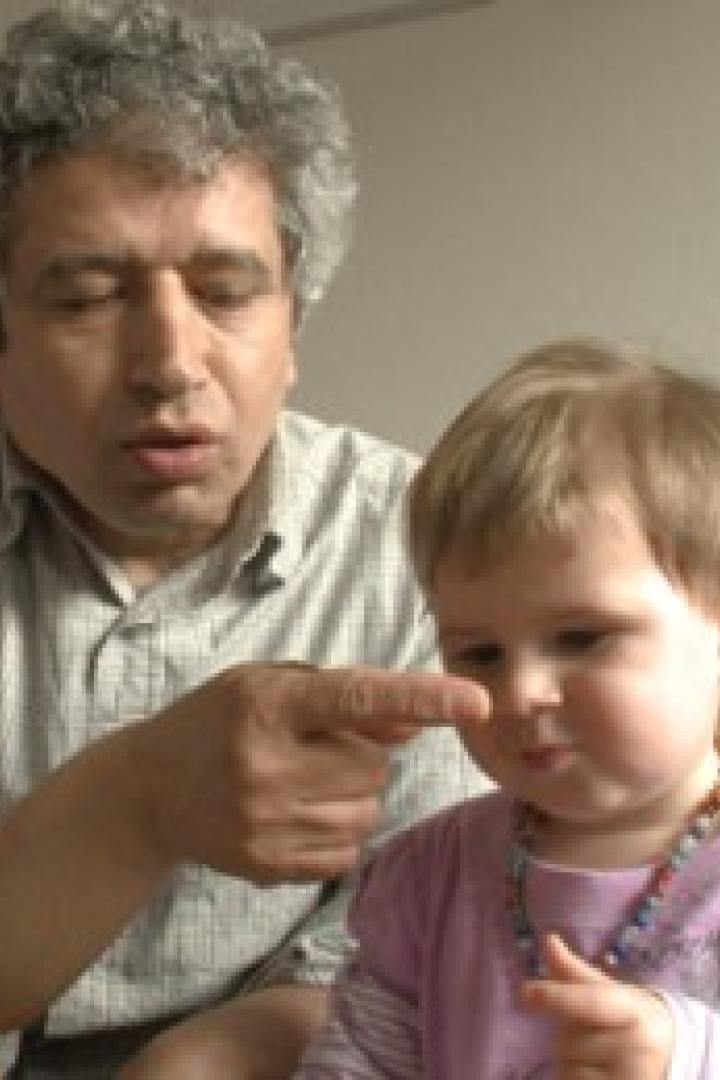 Ein Mann zeigt mit dem Finger auf die Nase eines kleinen Kindes.