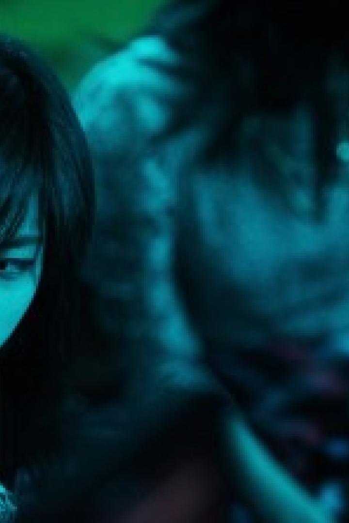 Eine junge Frau mit dunklen Haaren schaut nach unten.