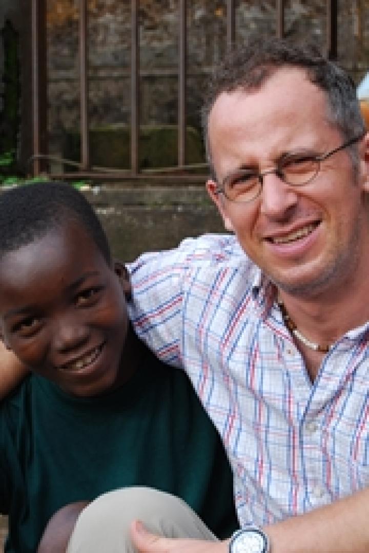 Ein lächelnder Mann mit Brille umarmt einen Jungen auf einer Treppe.