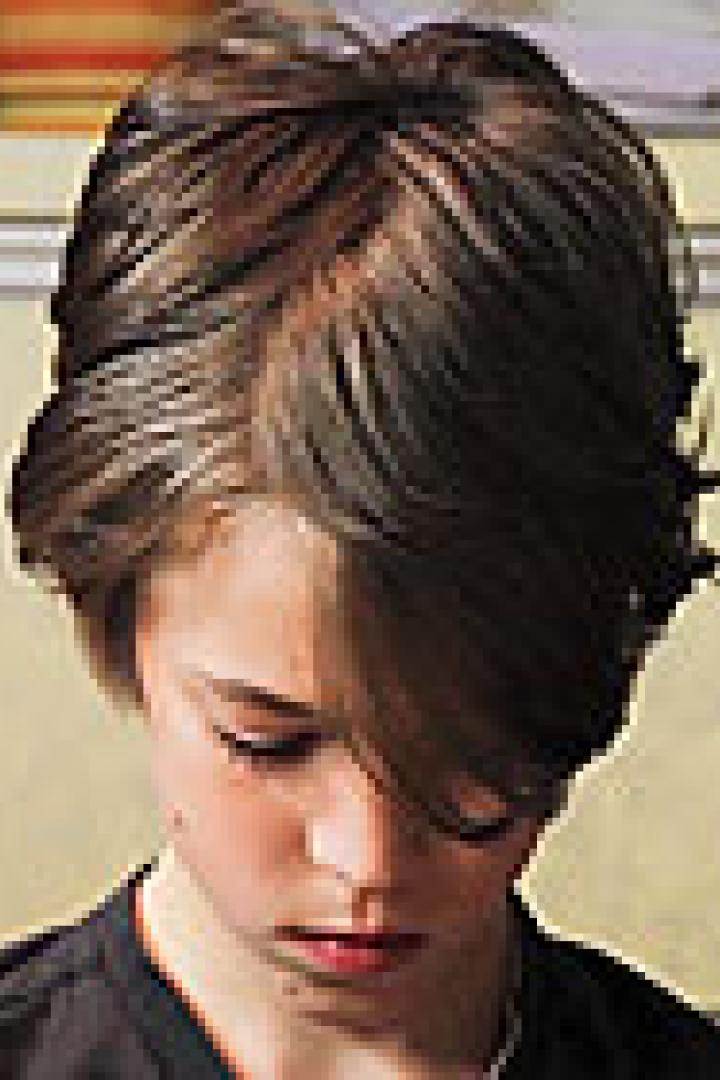 Ein junger Mensch mit braunen Haaren blickt nach unten.