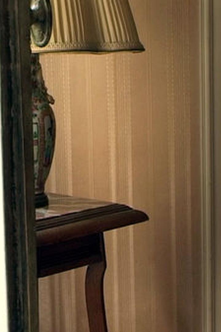 Eine Lampe mit beigem Lampenschirm steht auf einem kleinen Tisch.