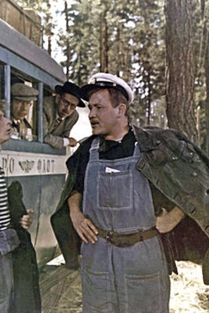 Zwei Männer in Arbeitskleidung stehen vor einem Bus in einem Waldstück.