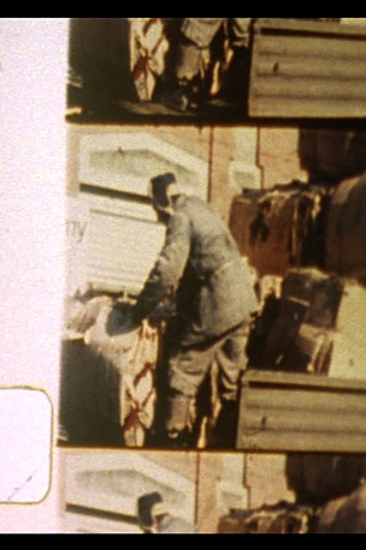 Ein Mann in Uniform hantiert mit Gepäckstücken auf einem Güterwagen.