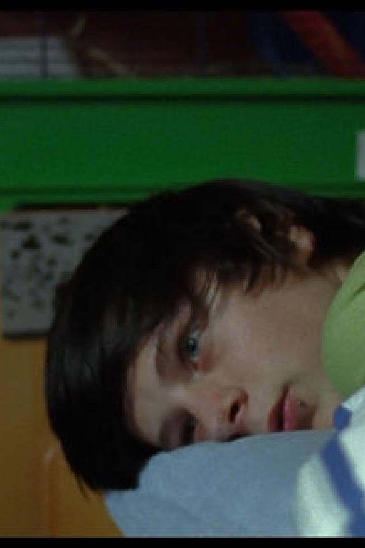 Ein junger Mann liegt auf einem blau-weiß gestreiften Kissen.