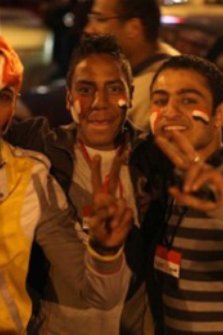 Drei junge Männer mit ägyptischen Flaggen auf ihren Gesichtern zeigen Victory-Zeichen.