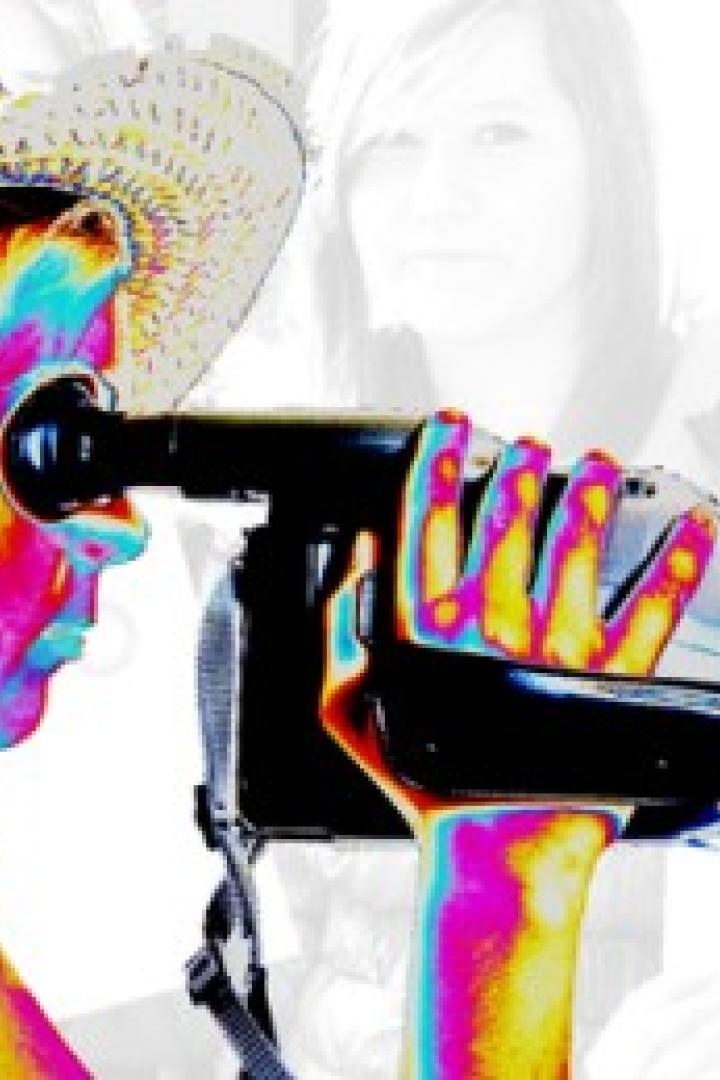 Eine Frau mit Hut filmt mit einer Videokamera.