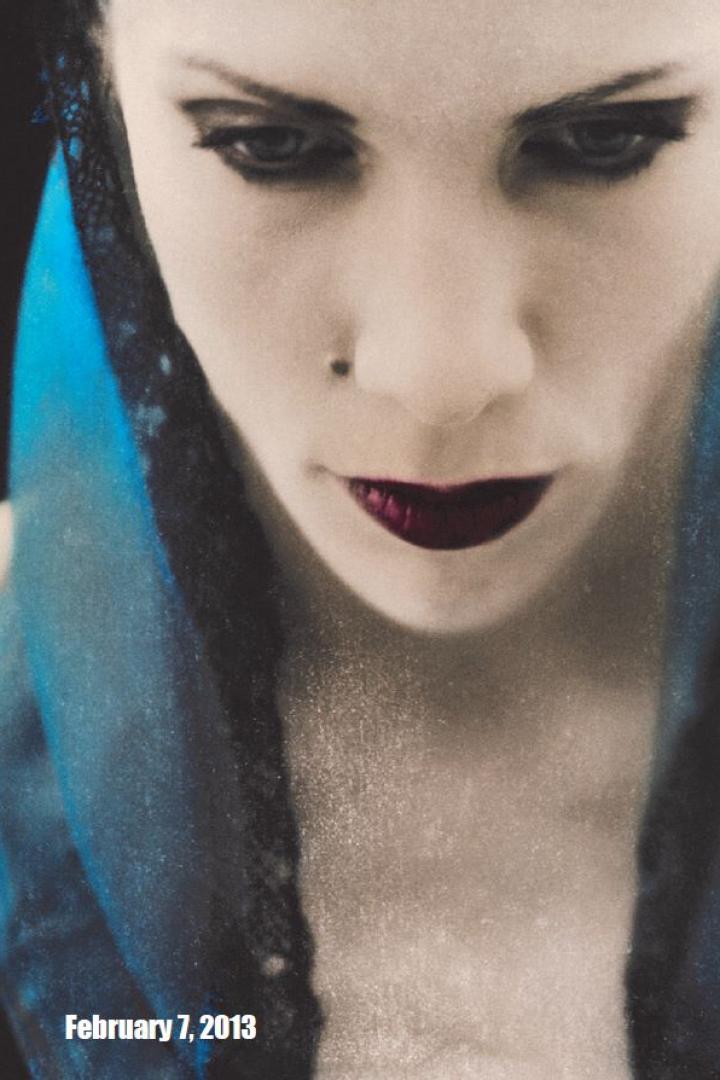 Nahaufnahme einer Frau mit dunklem Lippenstift und blauem Schleier.