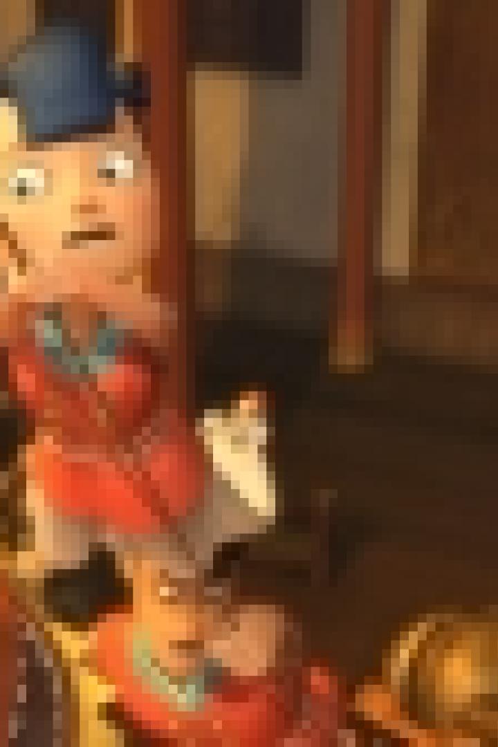 Eine animierte Figur in roter Kleidung und einem blauen Hut steht vor einem festlichen Hintergrund.