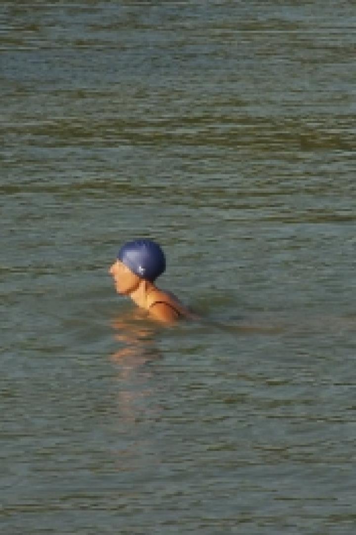 Eine Frau mit Badekappe schwimmt im Wasser.