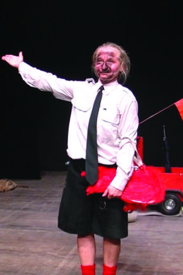 Ein Darsteller mit rußverschmiertem Gesicht auf einer Bühne mit einem roten Spielzeugauto.