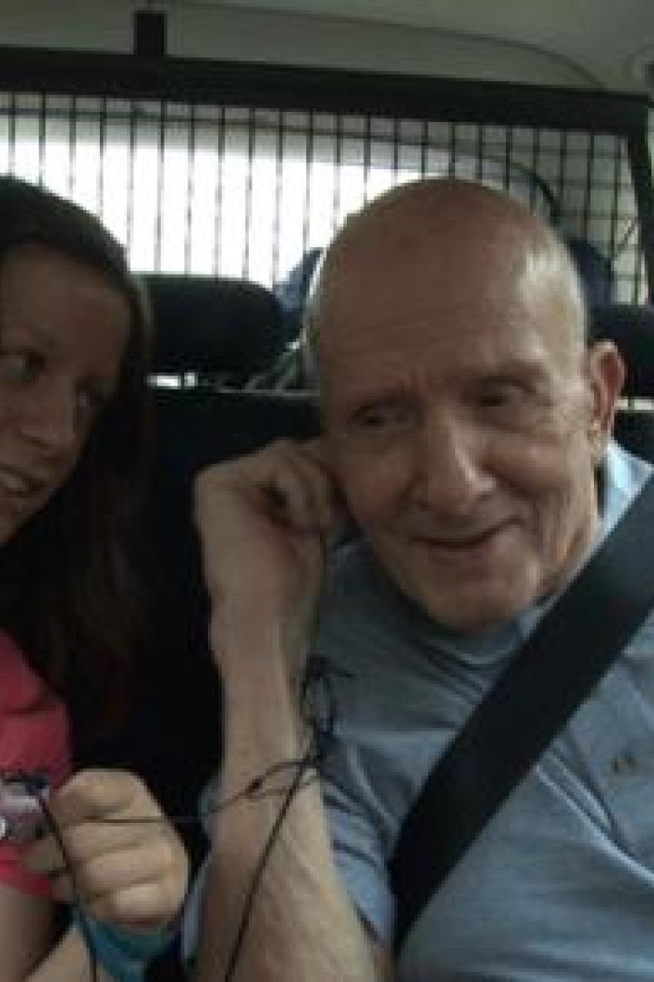 Eine junge Frau und ein älterer Mann sitzen angeschnallt im Auto.