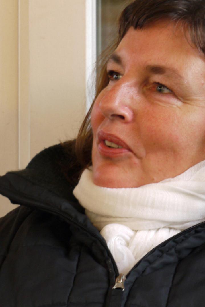 Eine Frau mit braunen Haaren und weißem Schal blickt nach oben.