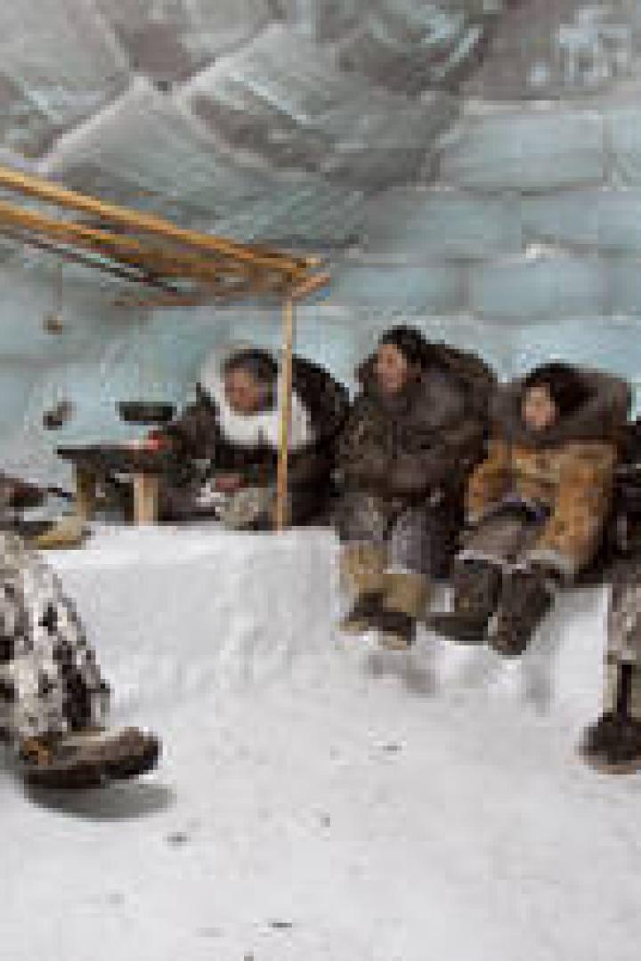 Eine Gruppe von Menschen sitzt in einem Iglu.