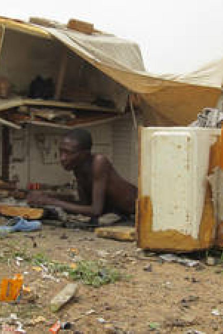 Ein Mann liegt in einer notdürftigen Hütte aus Müll auf einer Müllhalde.