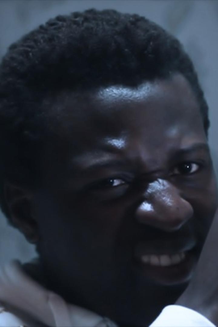 Ein Mann blickt grimmig in die Kamera, die Faust vor dem Mund.