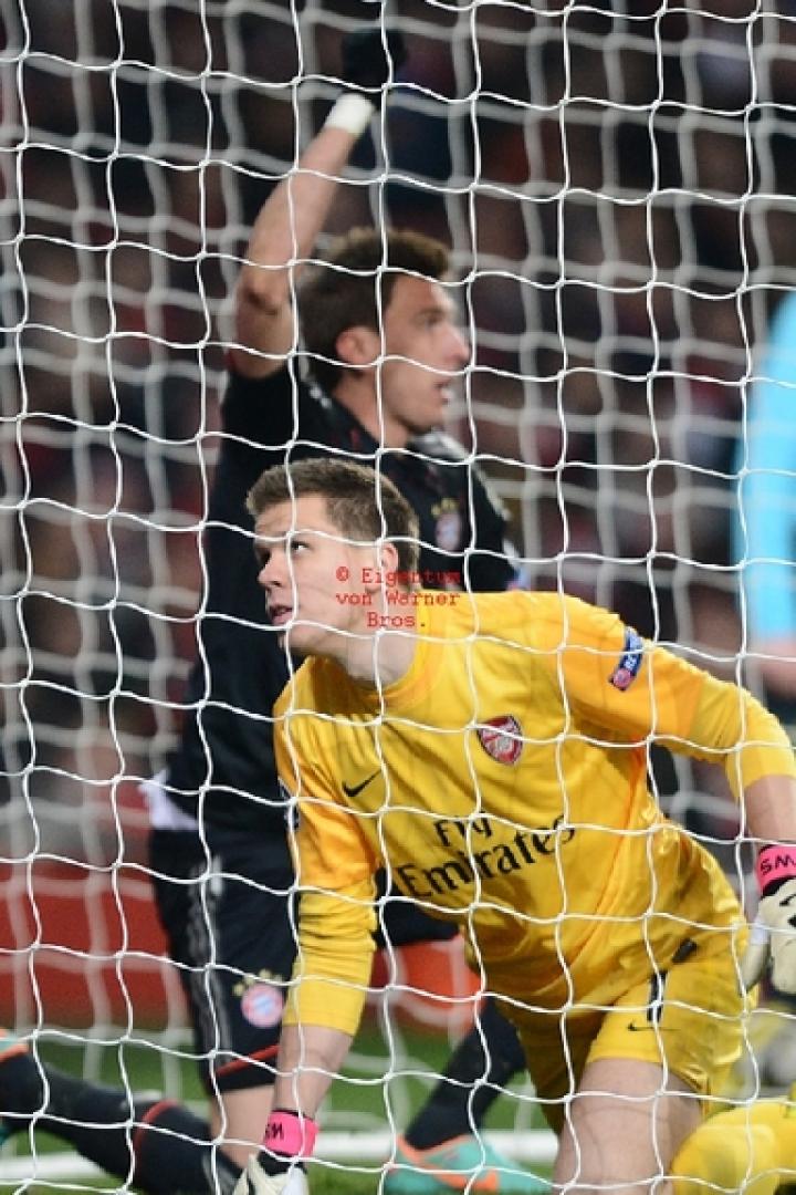 Ein Fußball fliegt in das Netz, während der Torwart zusieht.