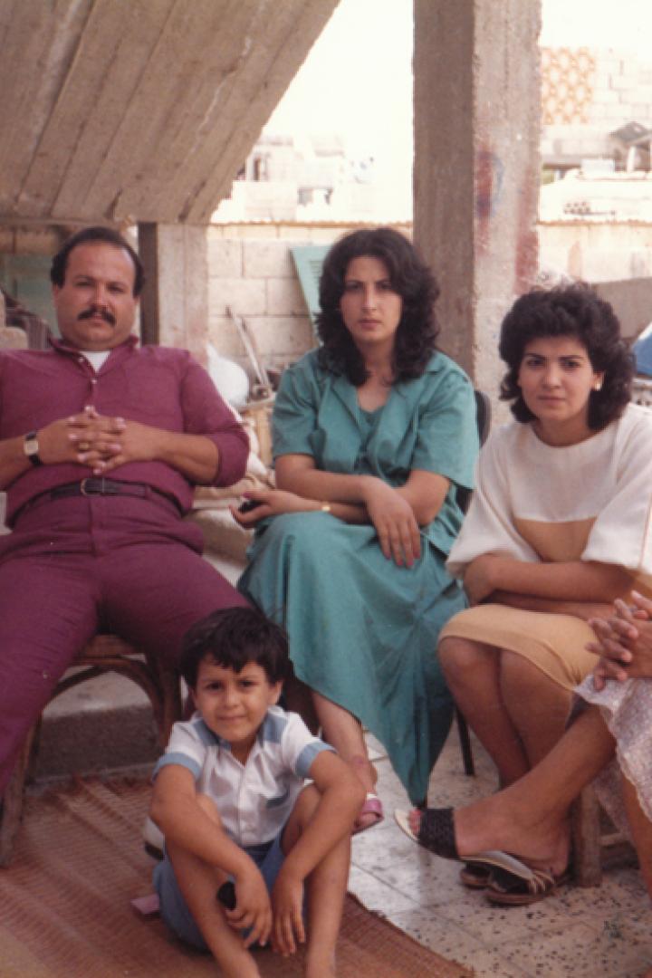Eine Familie sitzt im Freien vor einem unfertigen Gebäude.