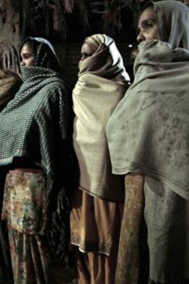 Eine Gruppe verschleierter Frauen steht vor einer Mauer.