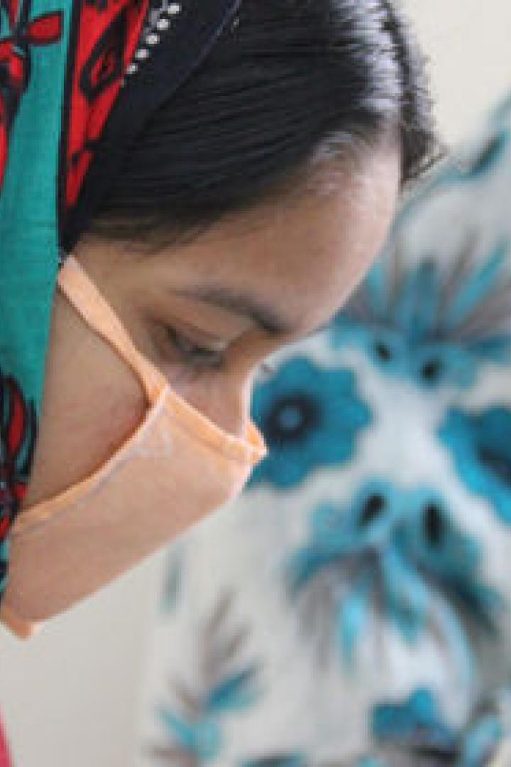 Zwei Frauen mit Gesichtsmasken arbeiten an Nähmaschinen.