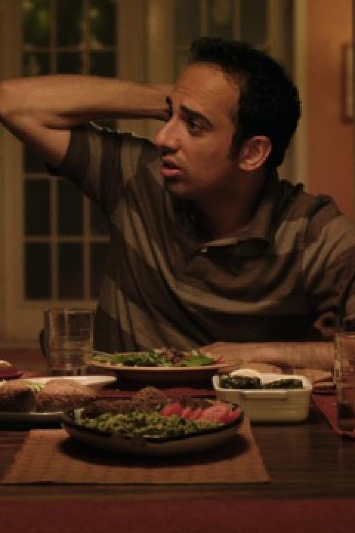 Drei Personen sitzen an einem Tisch mit Speisen und scheinen sich angeregt zu unterhalten.