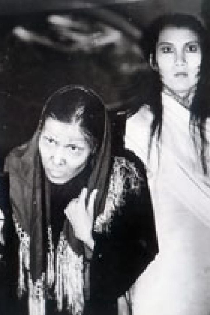 Zwei Frauen, eine mit einer Kerze, posieren in einem Schwarzweißfoto.