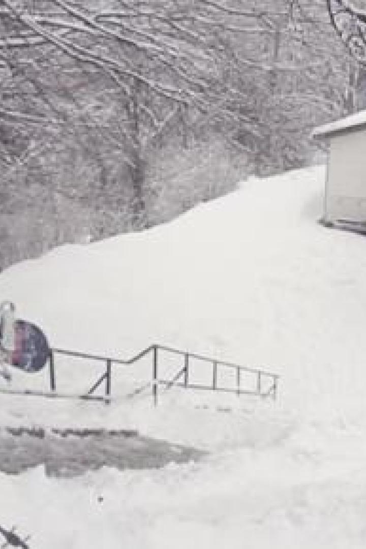 Ein Mann mit Snowboard steigt eine verschneite Treppe hinauf.