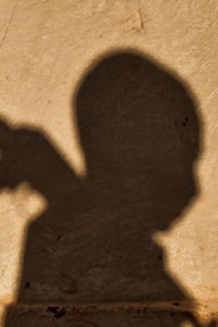 Der Schatten eines Kindes, das mit einem Spielzeuggewehr spielt, ist an einer Wand zu sehen.