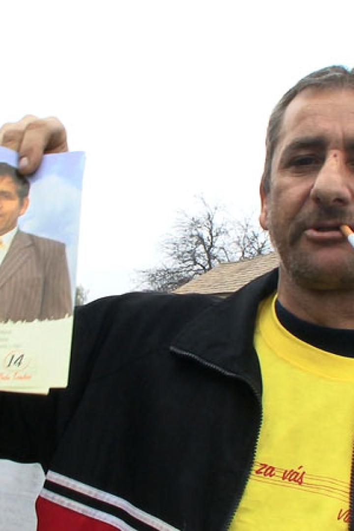 Ein Mann hält ein Foto eines anderen Mannes in der Hand und raucht eine Zigarette.