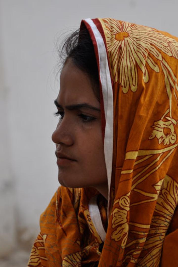 Eine junge Frau mit einem orangefarbenen Kopftuch mit Blumenmuster.