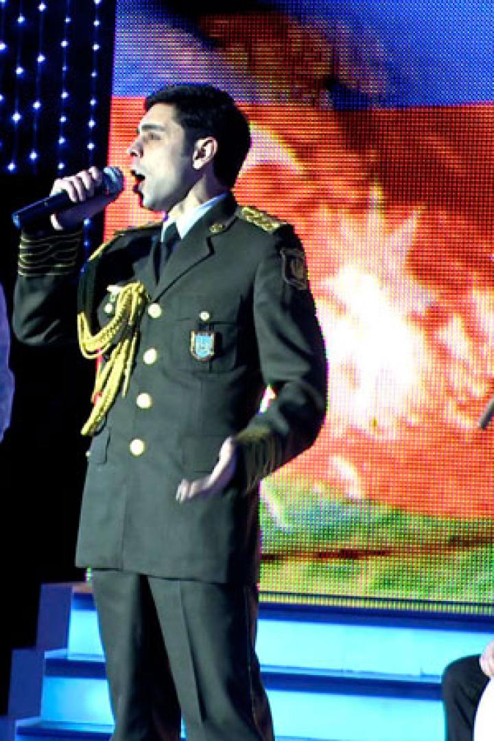 Ein Sänger in Uniform tritt mit Musikern auf einer Bühne auf.