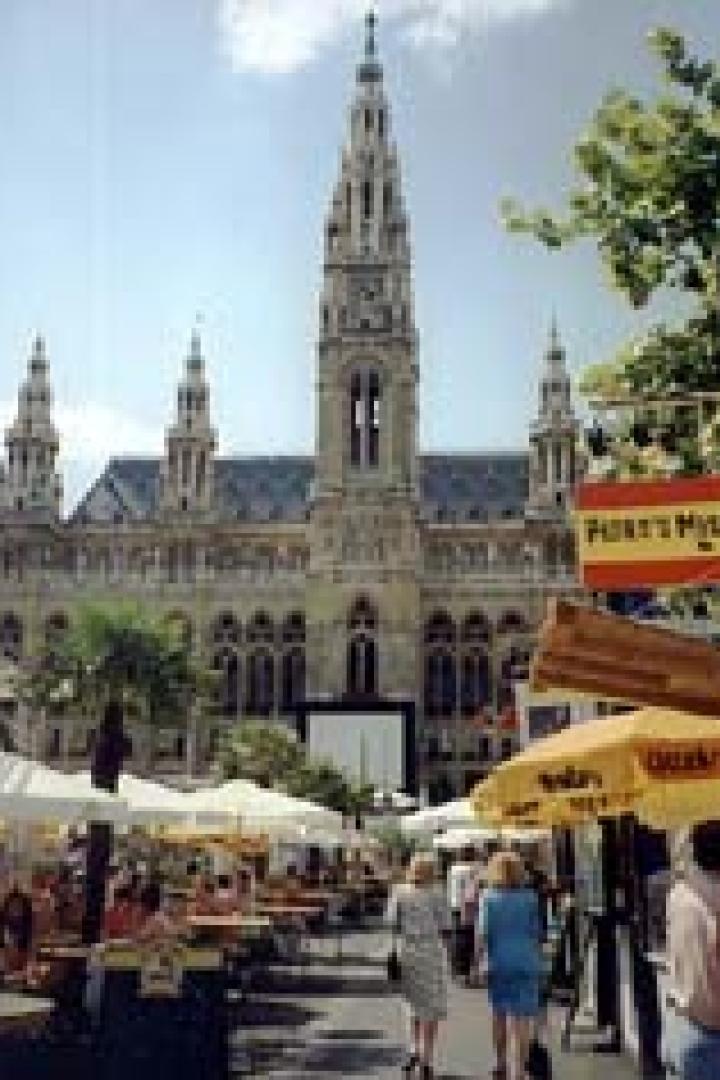 Das Wiener Rathaus überblickt einen belebten Markt mit Essensständen.