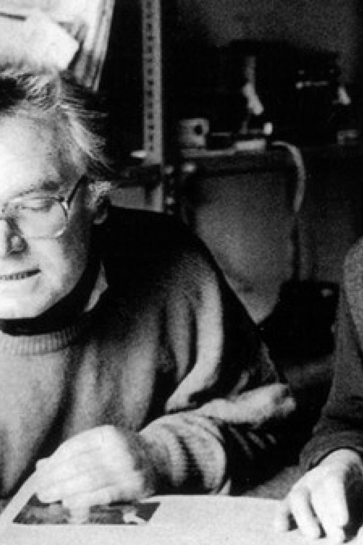 Zwei ältere Männer betrachten gemeinsam Fotos an einem Tisch.