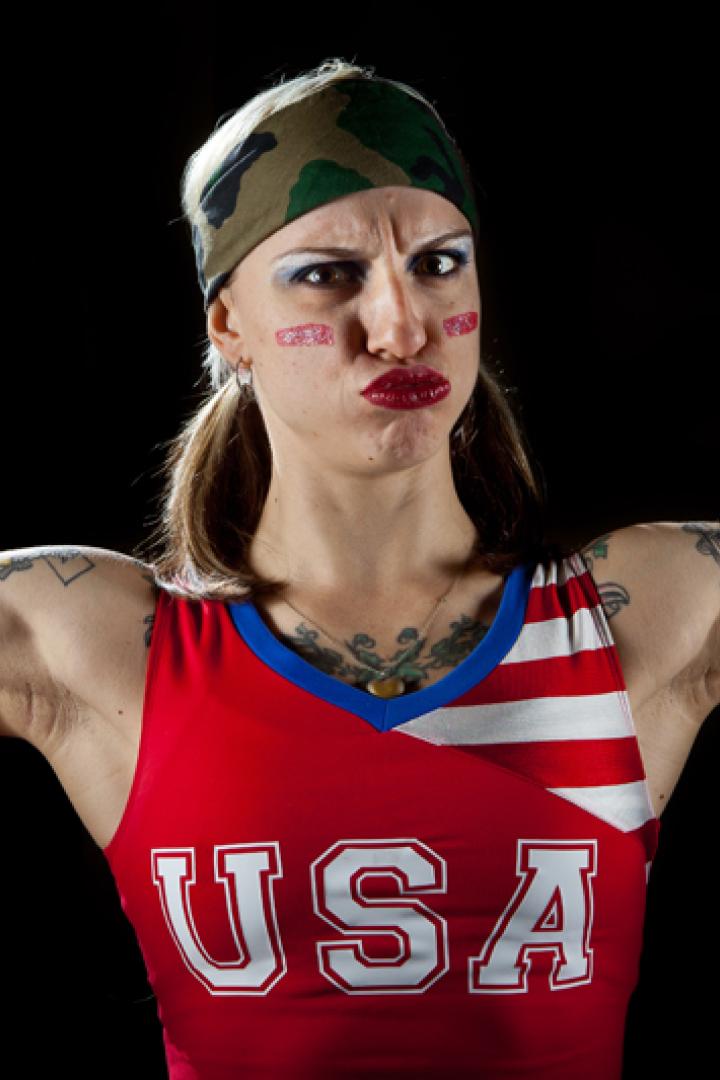 Eine tätowierte Frau im USA-Trikot spannt ihre Muskeln an.