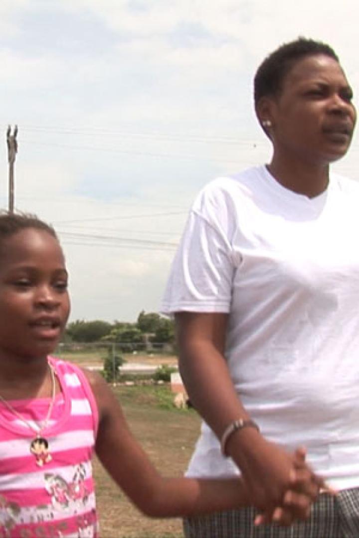 Eine Frau hält die Hand eines kleinen Mädchens in einem Park.