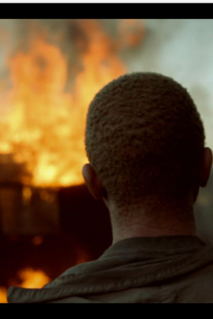 Ein Mann blickt auf ein brennendes Gebäude.