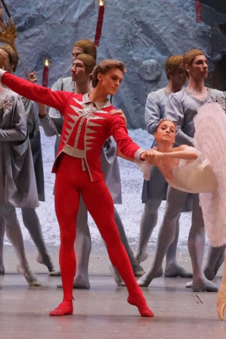 Eine Ballettaufführung mit einer Ballerina in Weiß und einem Tänzer in Rot im Rampenlicht.