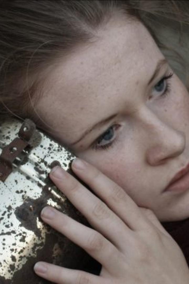 Eine Frau lehnt ihr Ohr an einen Metalleimer; Filmposter für „You & Me“.