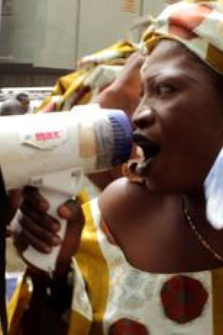 Eine Frau ruft mit einem Megaphon auf einer Demonstration, während sie eine Wasserflasche hält.