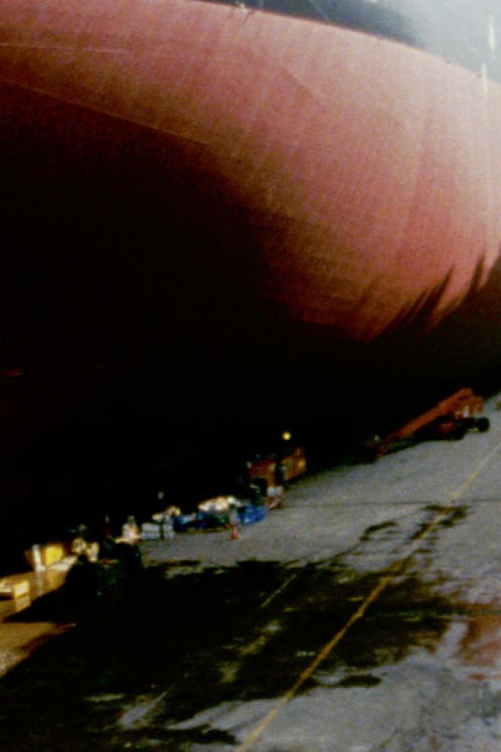 Ein großes Schiff im Trockendock, wo Wasser aus einer Öffnung abgelassen wird.